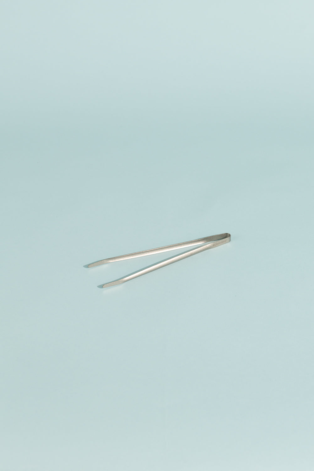 Evernew Meshitsucam Tongs displayed against a light blue background, showcasing their sleek titanium design.