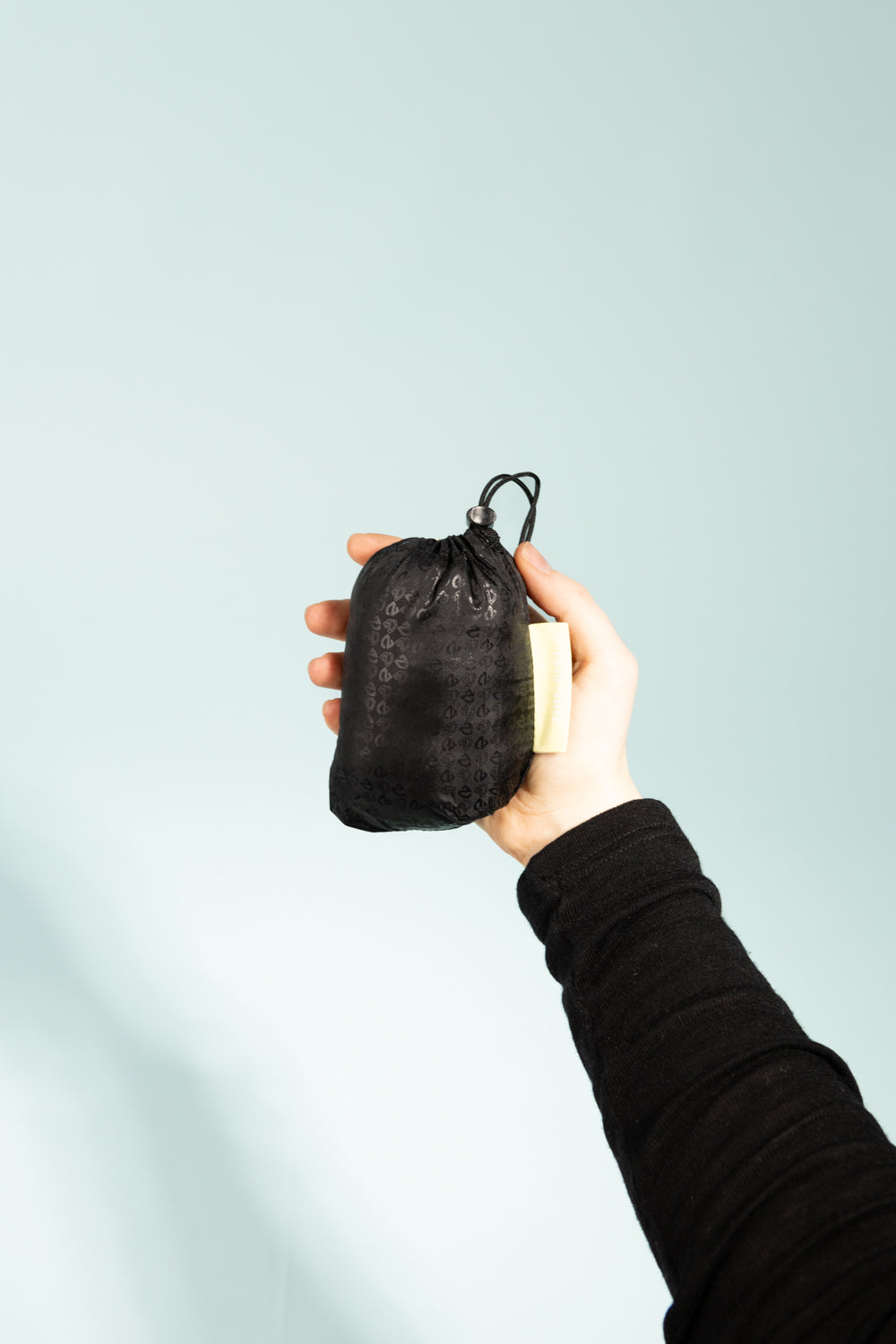 Nemo Fillo Elite Pillow - Black Pearl stored in a compact black carrying pouch held by a person.