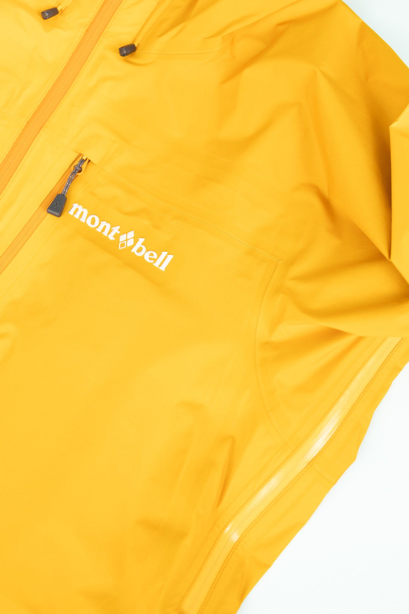 Montbell US Men's Tempest Jacket - Orange close-up of the jacket fabric and logo.