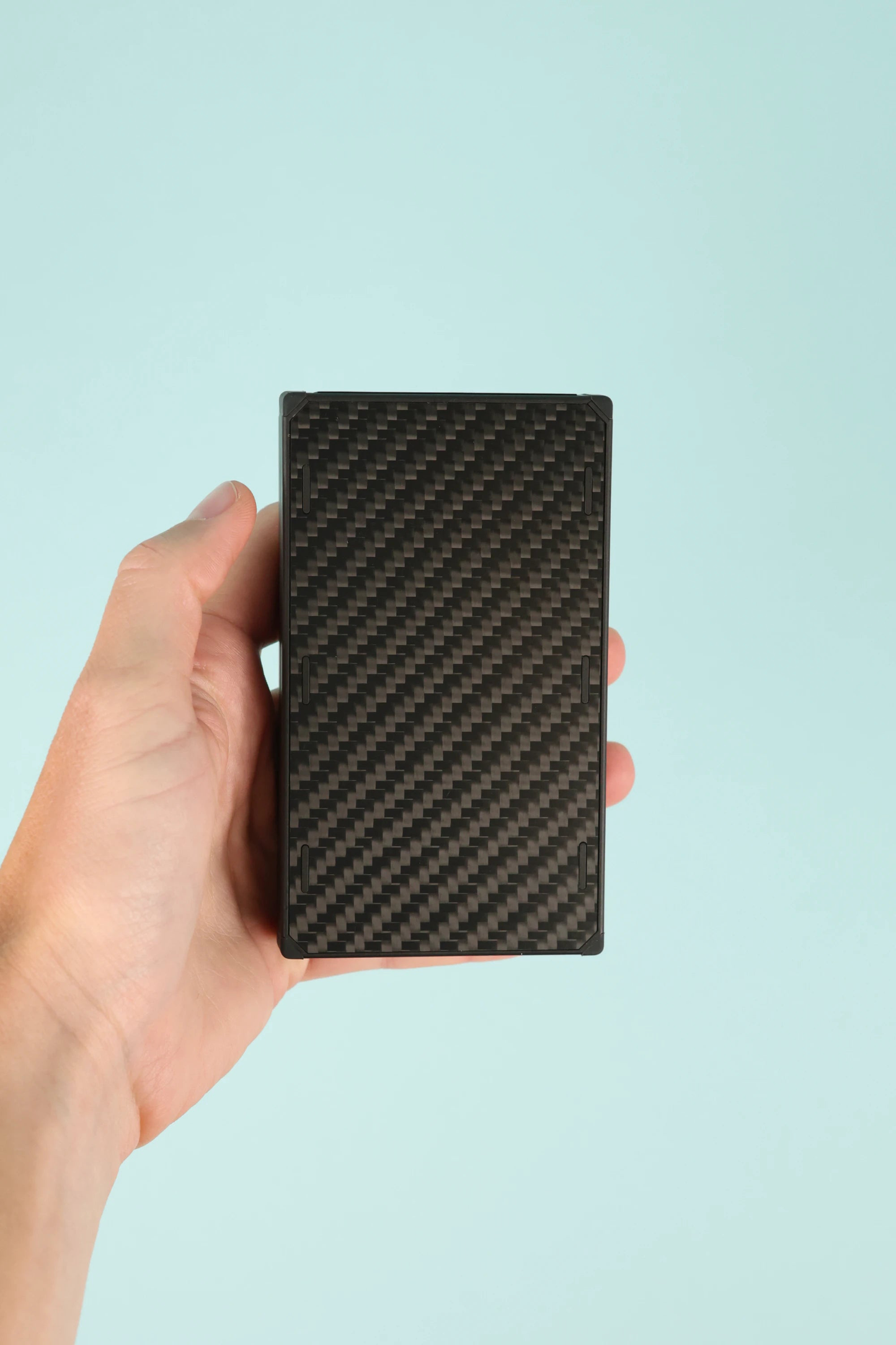 Nitecore NB20000 Powerbank Gen 3 held in hand against a light blue background, showcasing its sleek design.