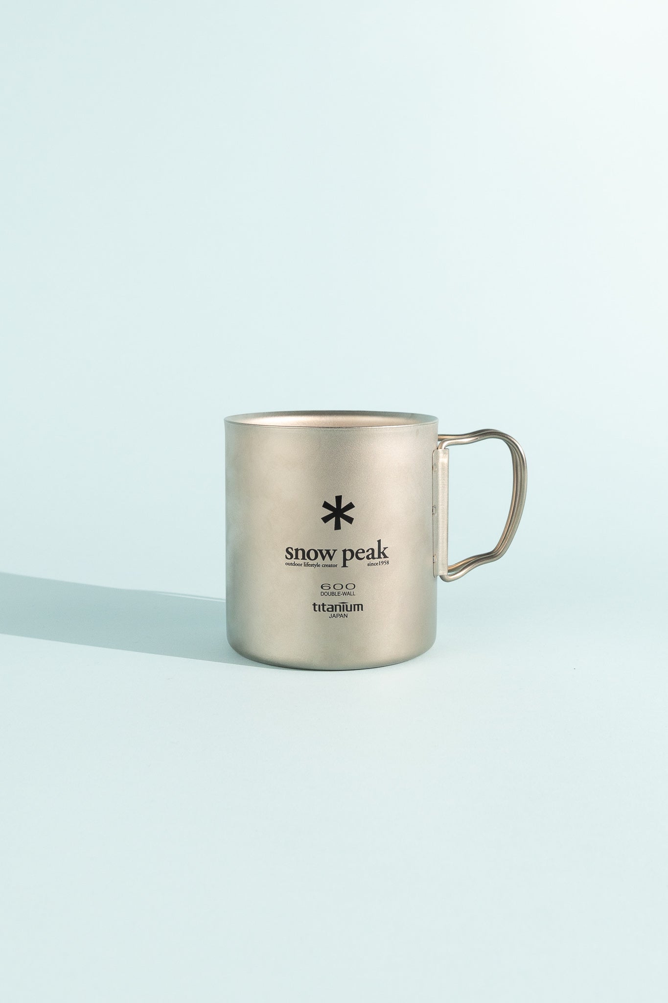 Titanium Double Wall Cup 600 by Snow Peak on a light blue background