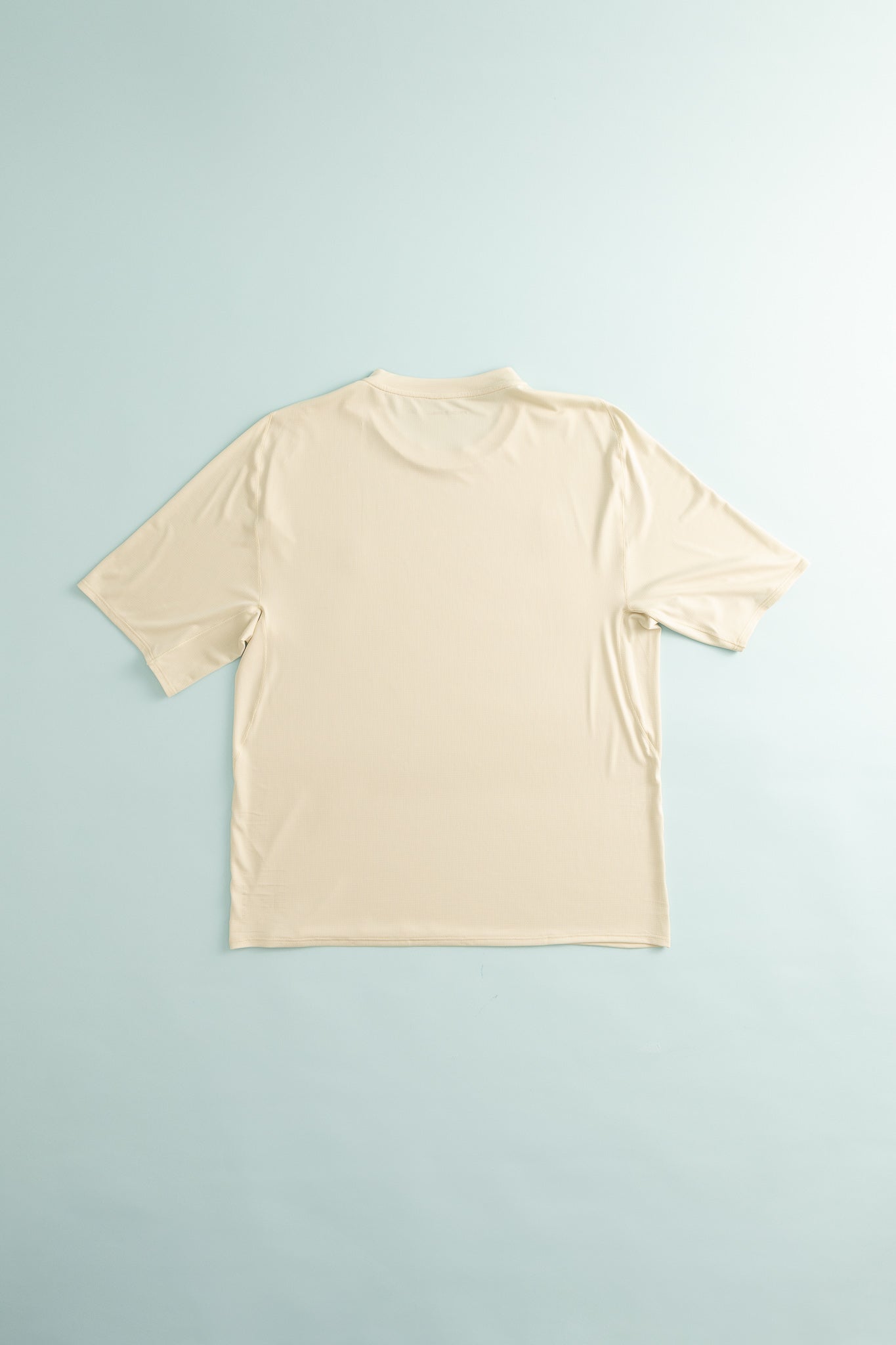 Back view of Lateral Peak Tee in Peyote color, showcasing its technical design for active movement.