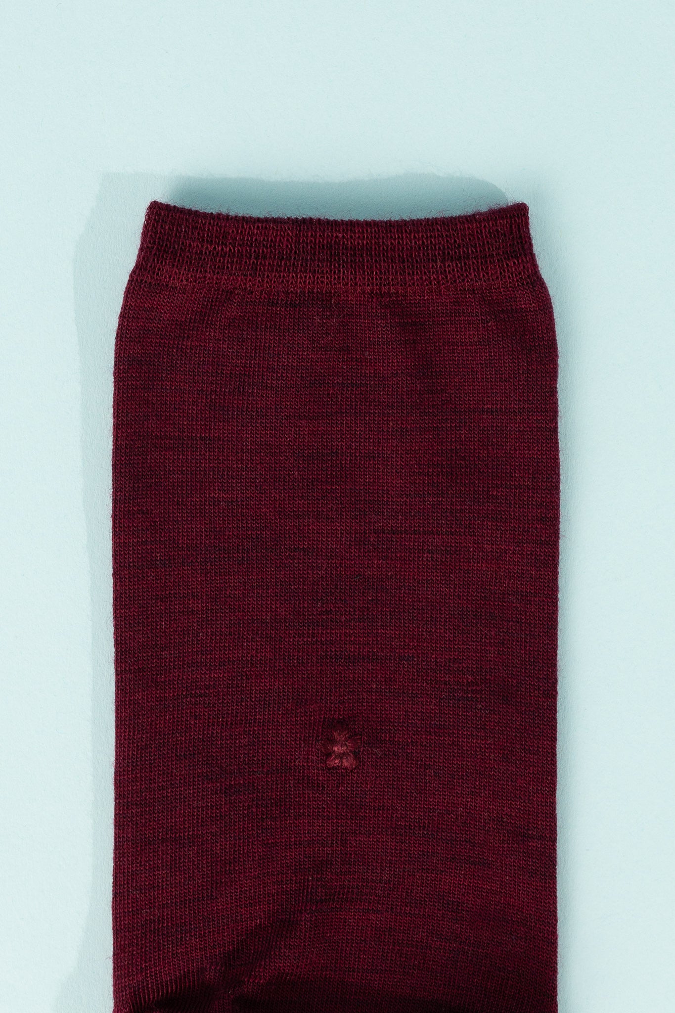 Laceflower Baselayer Tabi Socks in Bordeaux color against a light blue background.