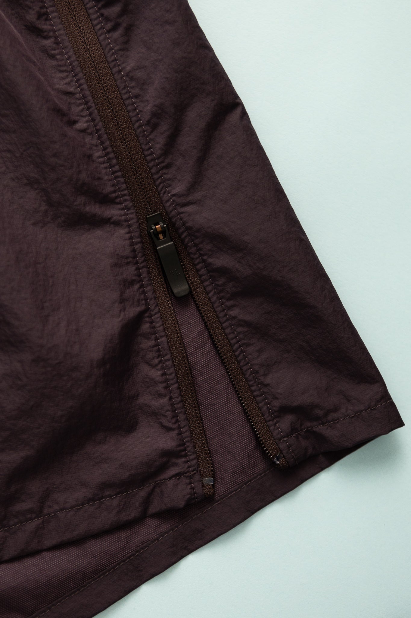 Detail of the zippered side of District Vision Women's Ultralight Nylon Zippered Shorts in Nightshade color.