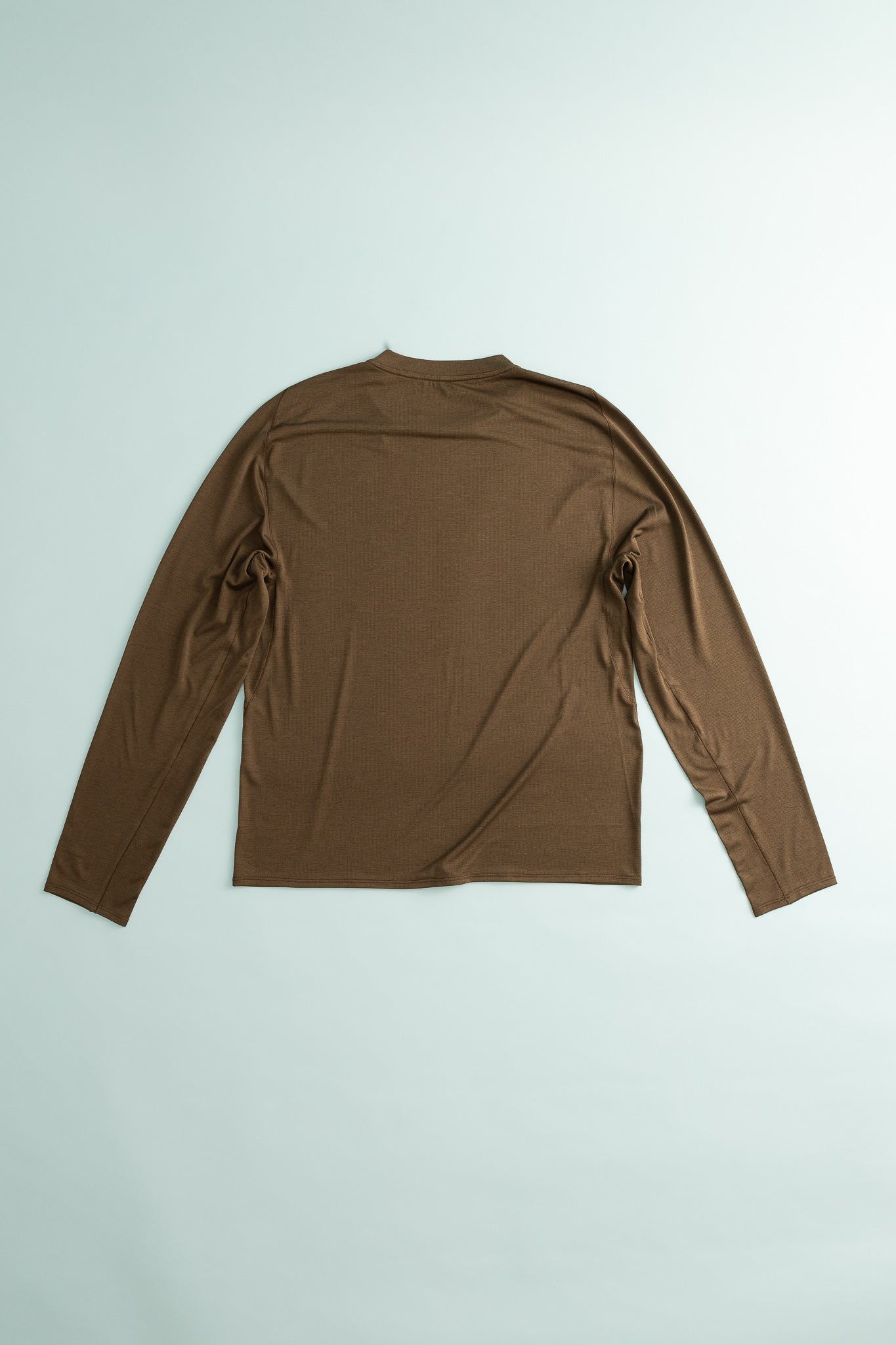 Back view of the Lateral Peak Long Tee in brown, showcasing its ergonomic design and athletic fit.