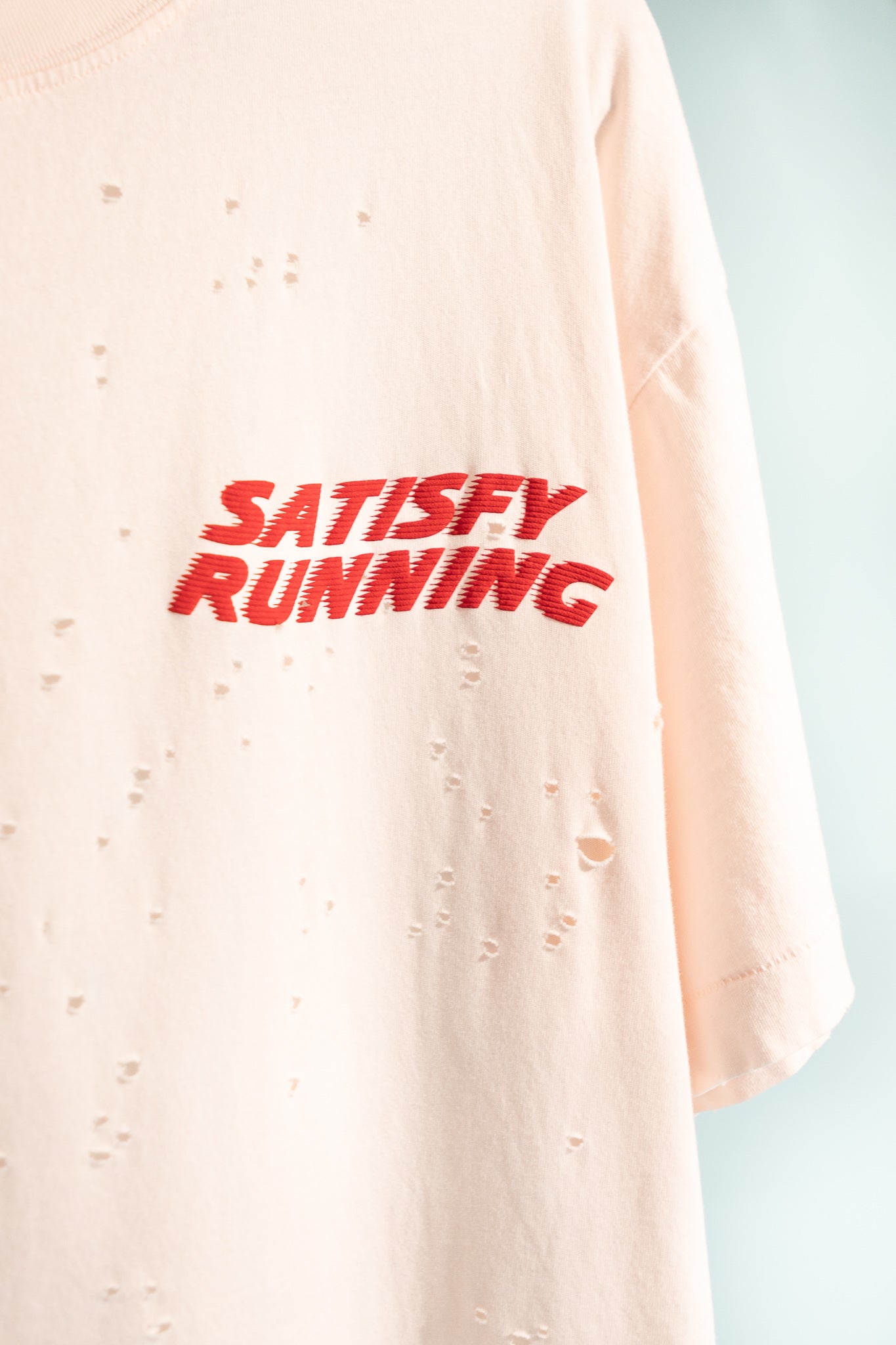MothTech™ T-Shirt in sun bleached rosewater with ventilation holes and red 'Satisfy Running' print.