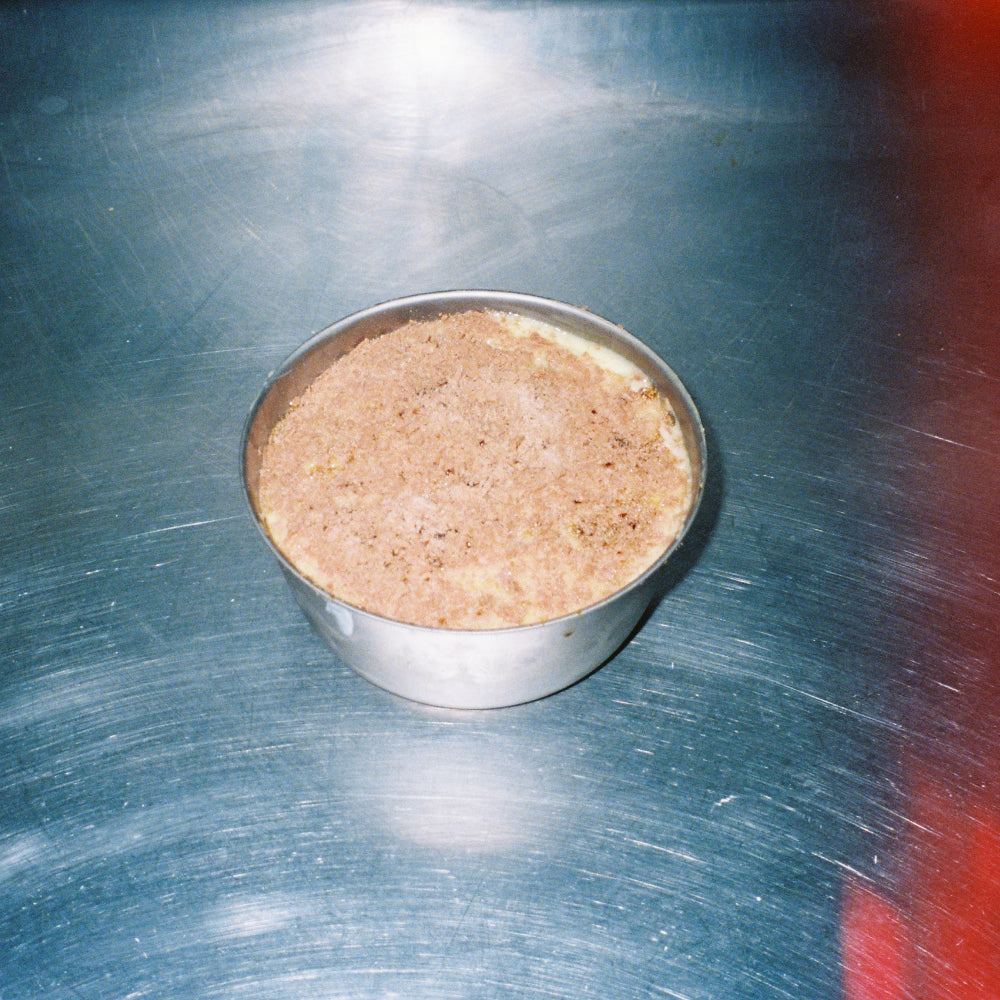 Delicious homemade Tiramisu in a silver bowl on a stainless steel surface.