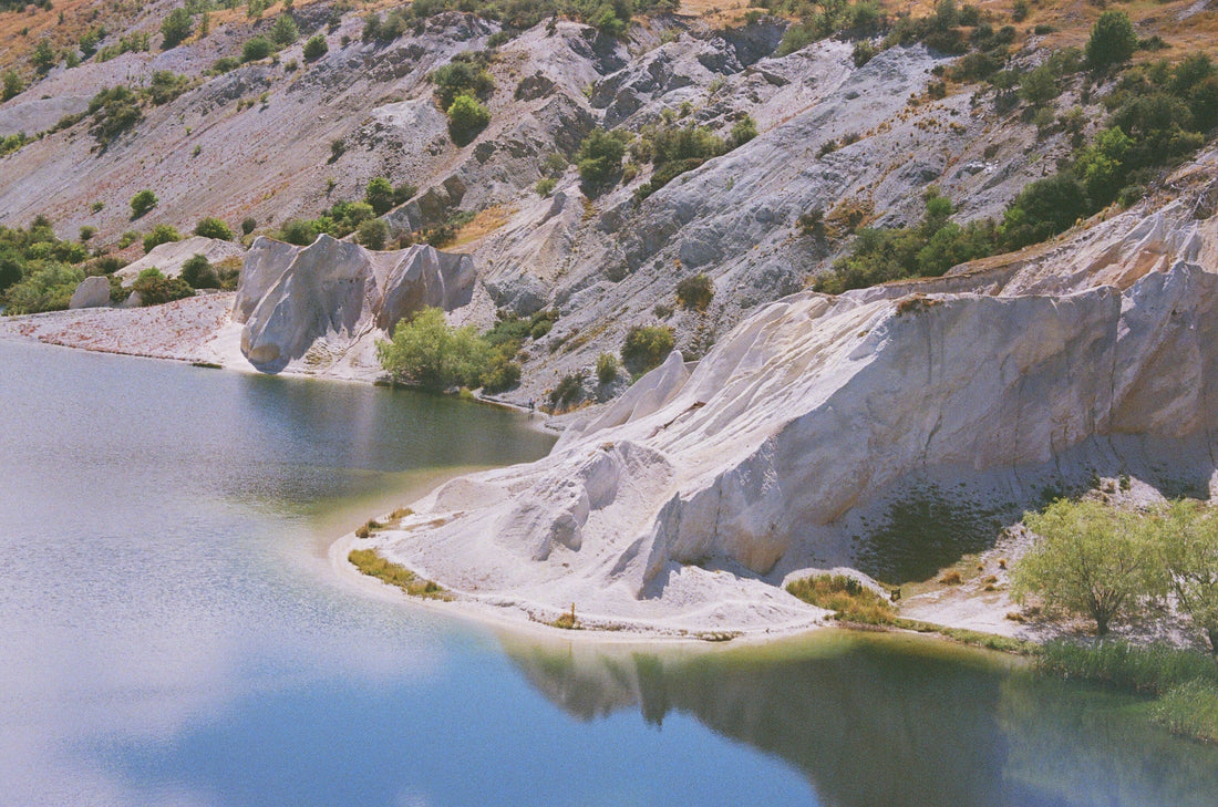 A serene landscape featuring a lake surrounded by beautiful rocky cliffs and greenery, showcasing a splendid outdoors scene.