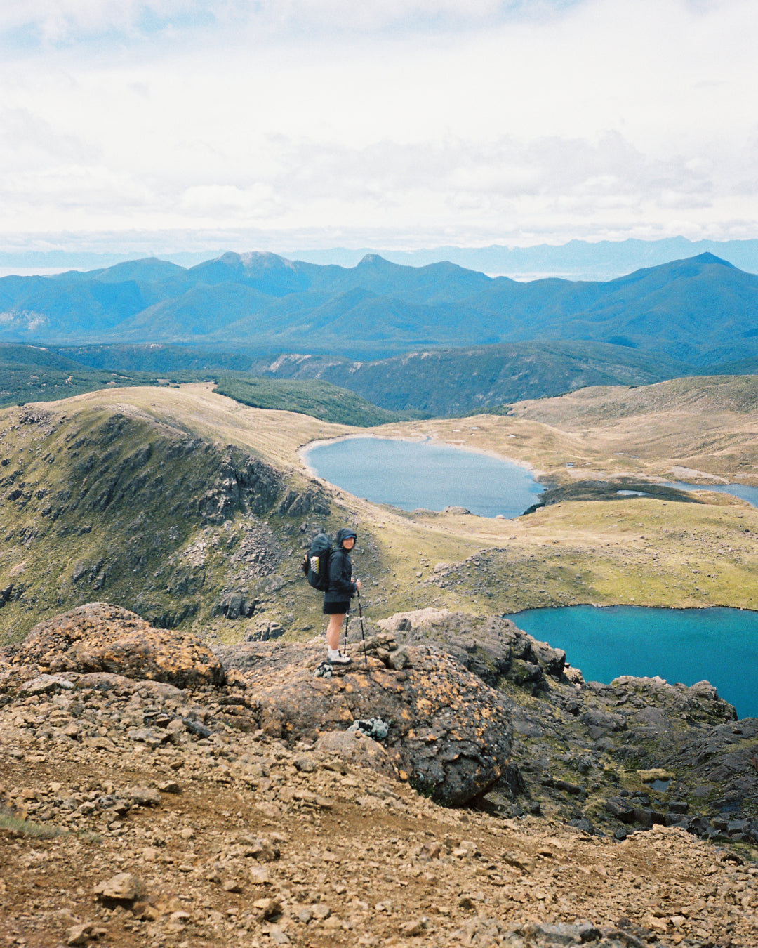 Hiker overlooking stunning lakes and mountains, ideal for inspiration from Shev's Packing List.