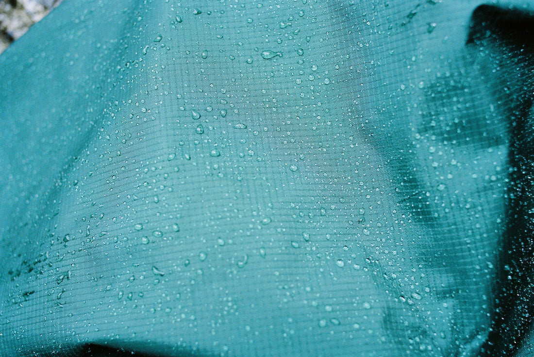 Close-up of a rain jacket with water droplets, showcasing its waterproof material and protective qualities.
