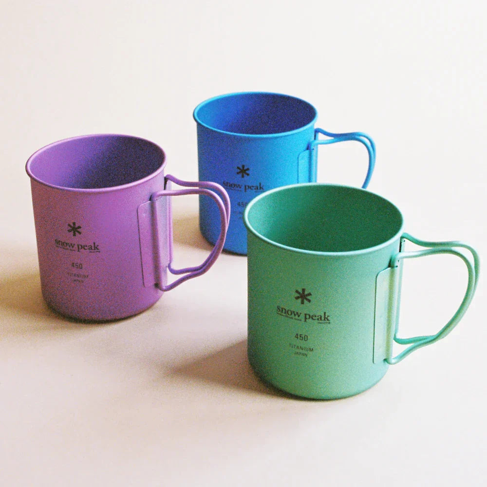 Colorful titanium mugs by Snow Peak in purple, blue, and green on a light background.