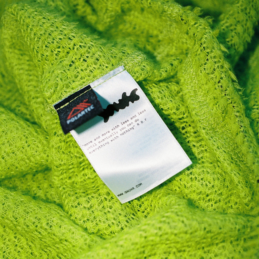 Label on vibrant green fuzzy fabric, highlighting texture and details of Buzzy and Fuzzy article.