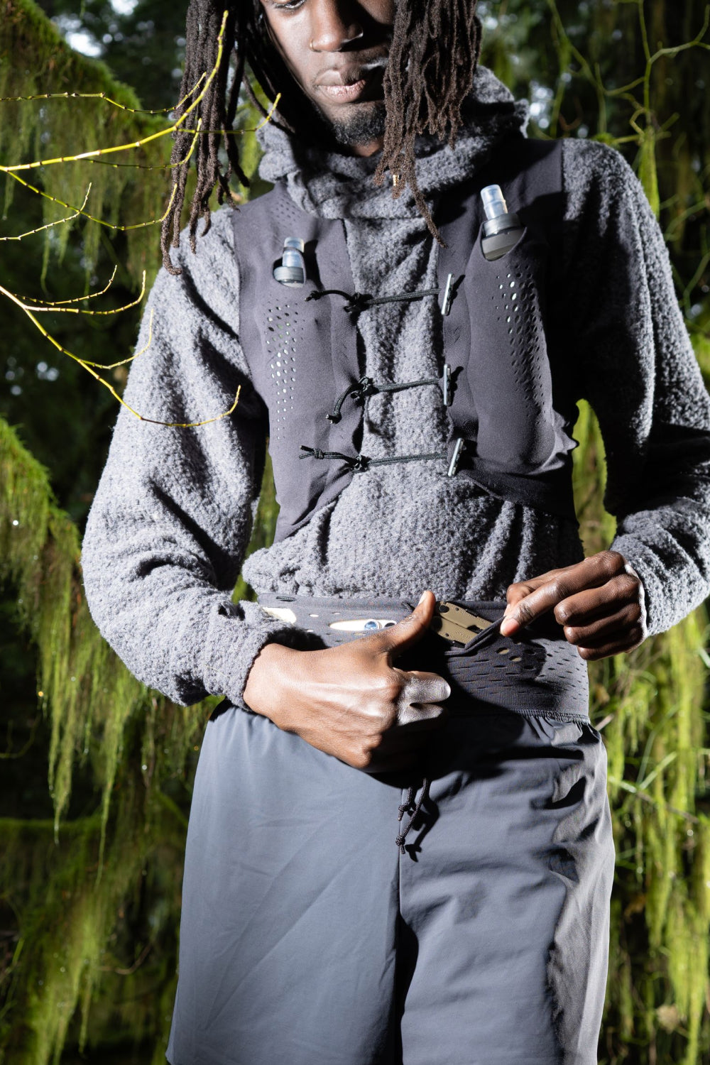 Model wearing the Warp Kit Vest - Anthracite, demonstrating its secure fit and integrated pockets in a natural setting.