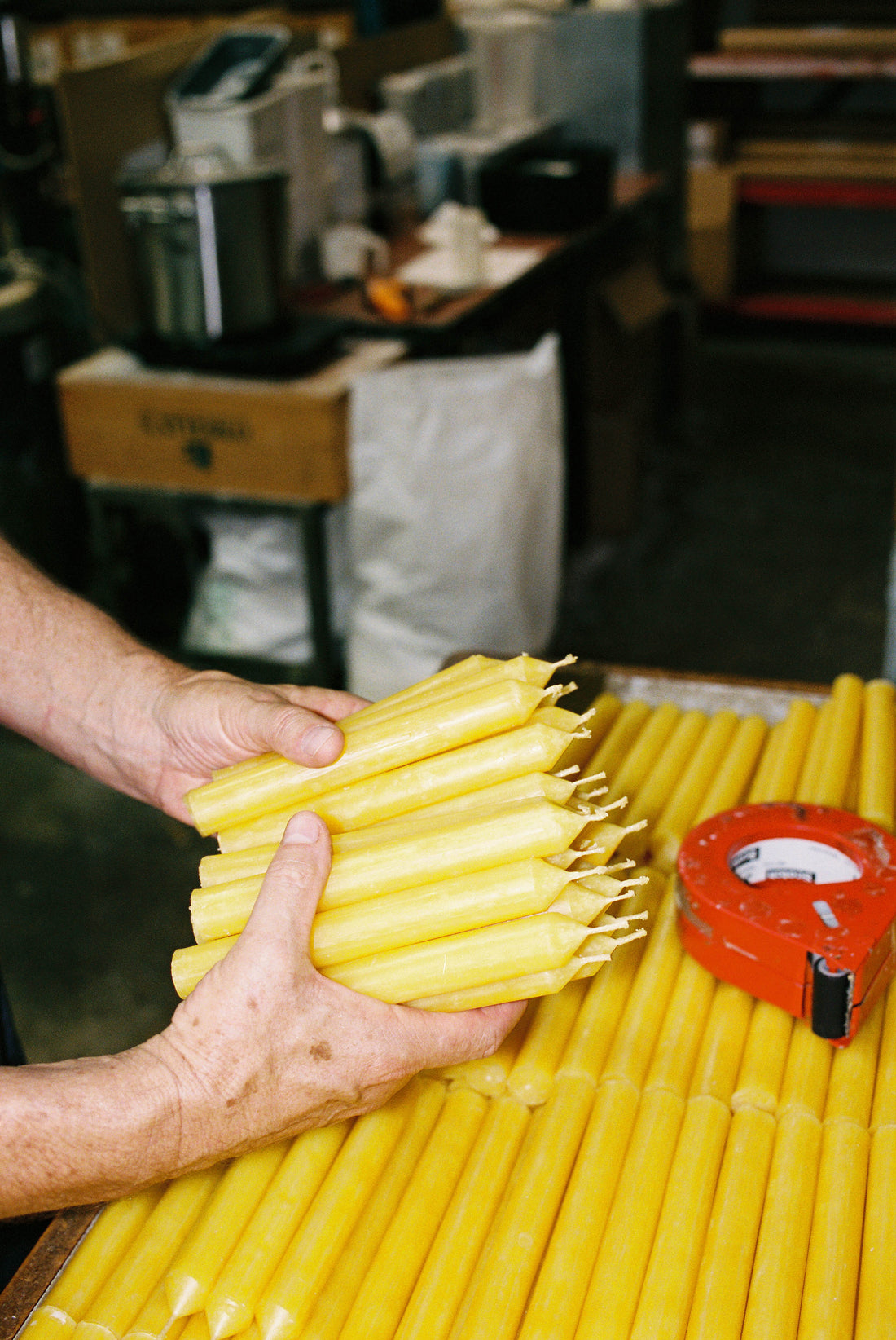 Coffee Outdoors x National Candles Hut Candles being hand-holding a bundle of yellow candles in a candle workshop.