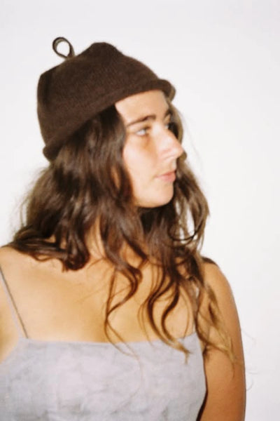 Bonnie Wroe Loop Hat - Chocolate worn by a woman with long hair, showcasing its unique design.