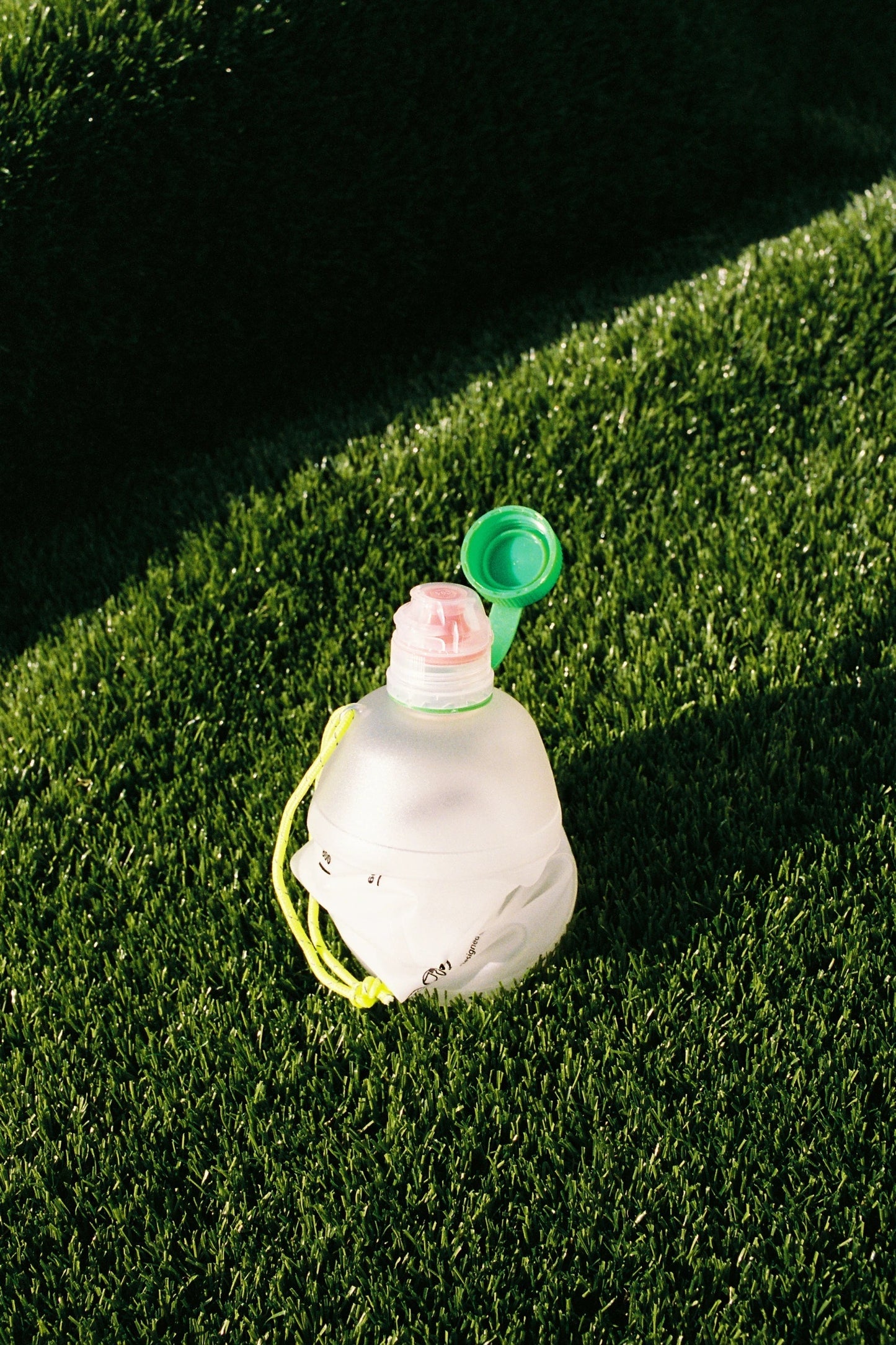 CNOC Vesica 1L Collapsible Bottle 28mm Thread on grass, showcasing its eco-friendly design and storage capability.