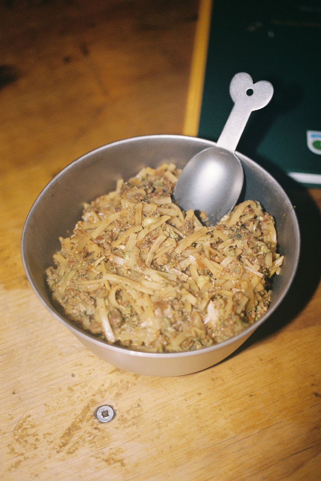 Firepot Spicy Pork Noodles in a bowl with a small spoon ready to enjoy a flavorful meal.