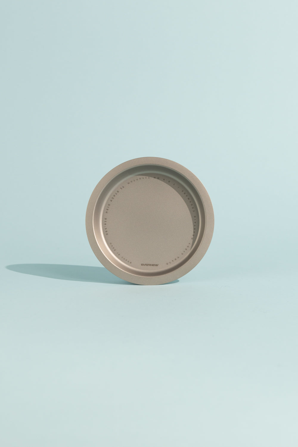 Evernew Titanium Stack Dish/Plate on a light blue background, showcasing its lightweight and stackable design for outdoor meals.