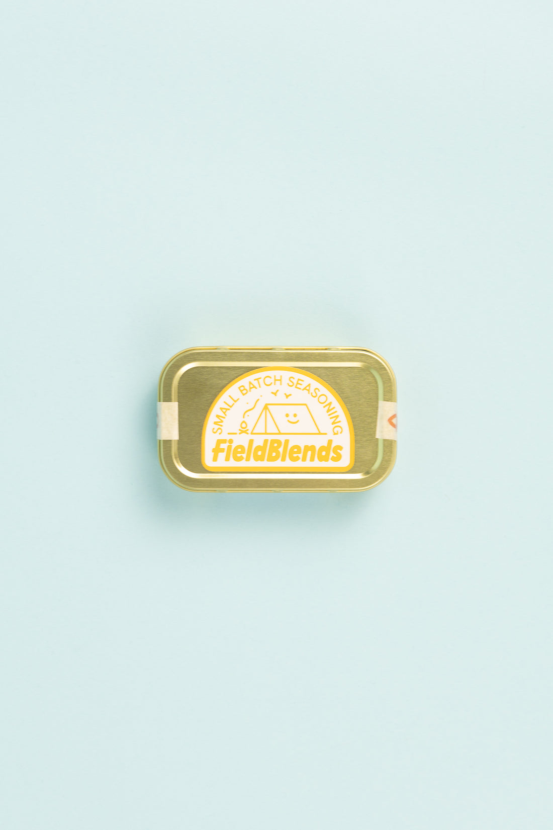 Field Blends Lemon, Sumac & Green Herb camping tin on a pastel background.