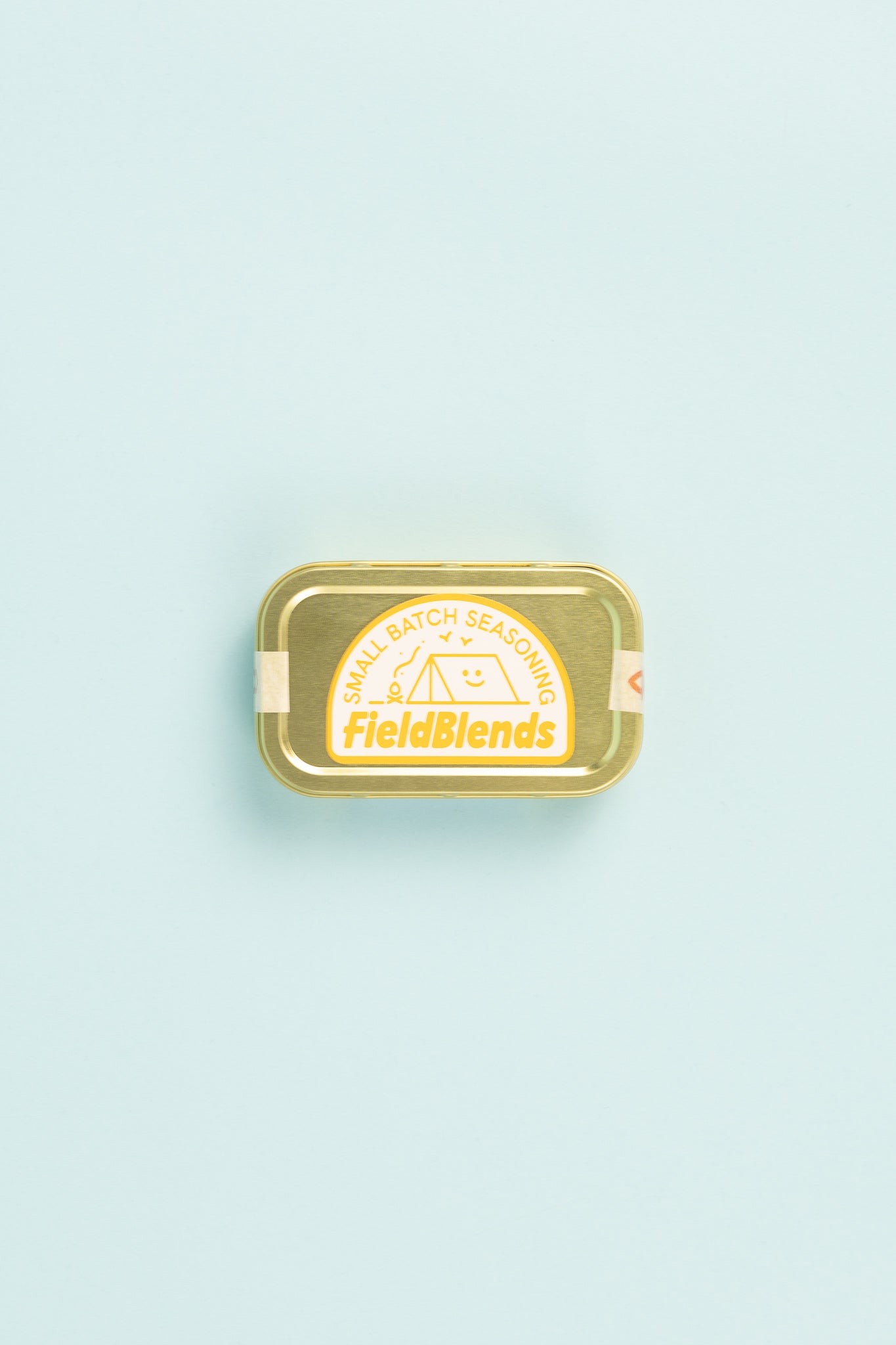 Field Blends Lemon, Sumac & Green Herb camping tin on a pastel background.