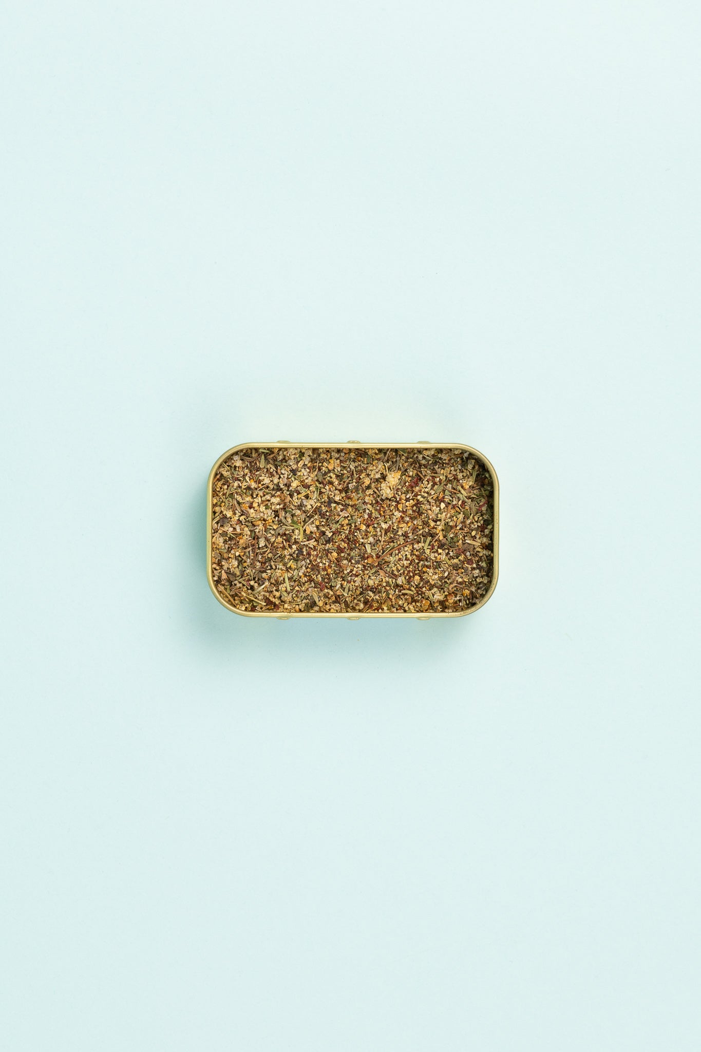 Field Blends Lemon, Sumac & Green Herb Camping Tin with spice blend on light background.