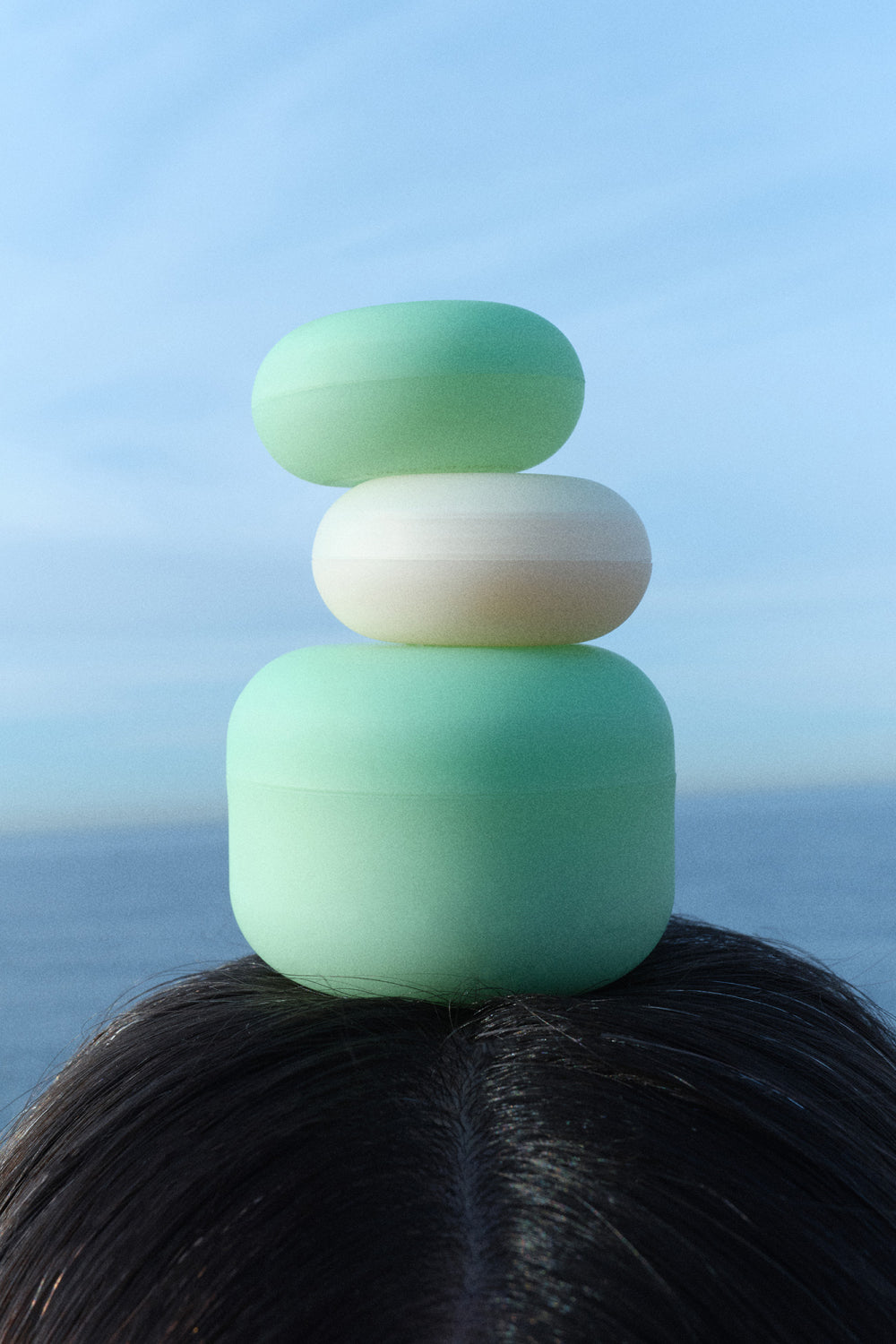 OEM Soothing Cream containers stacked on a person's head against a blue sky and ocean background.