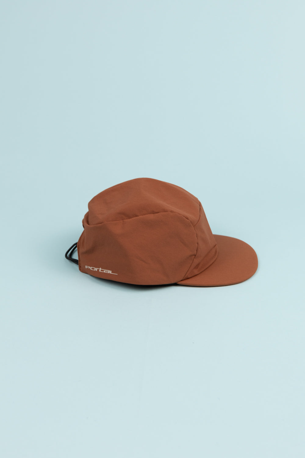 Portal Radius Cap in brown, lightweight and stretchy for a secure fit, ideal for running and everyday wear.
