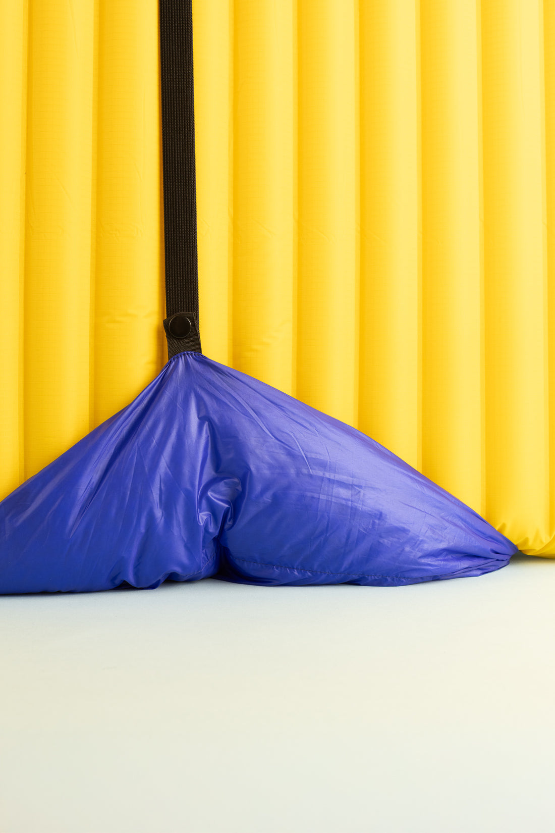 Blue padded corner of a yellow inflatable mattress, showcasing its design and attachment features.