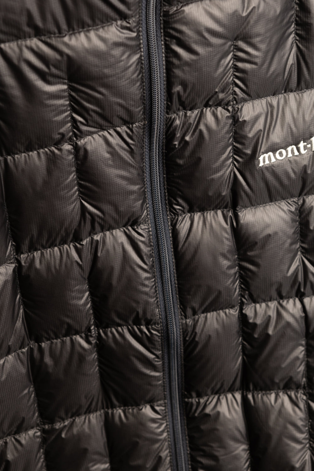 Montbell US Men's Plasma 1000 Down Jacket - Black close-up showing quilted design and logo.