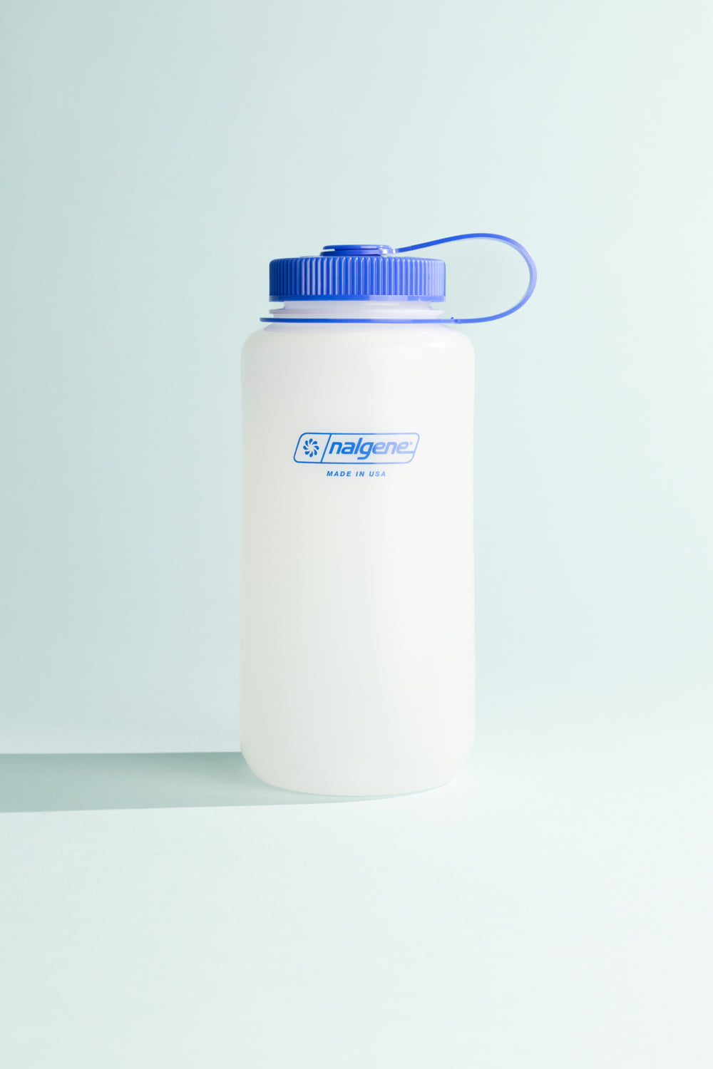 Nalgene Ultralite W/M 1L water bottle with blue cap and handle on a light background.
