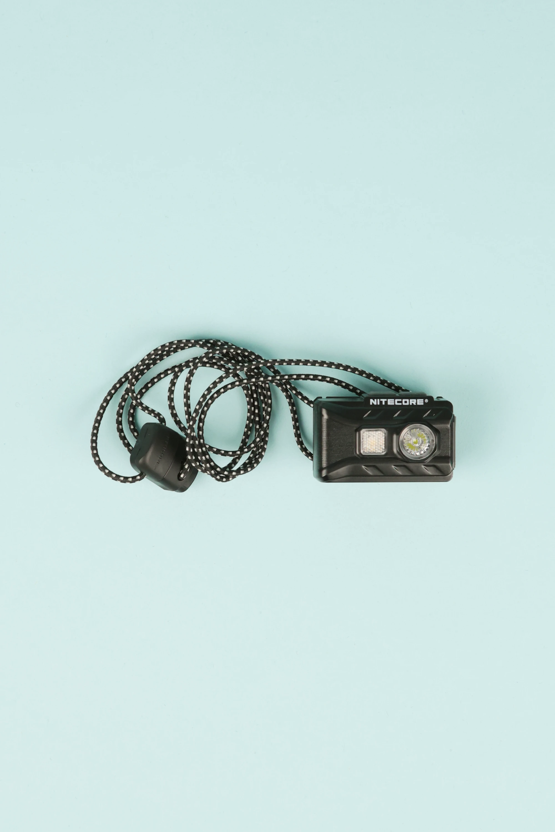 Nitecore NU20 - Classic lightweight headlight with a cord on a blue background.