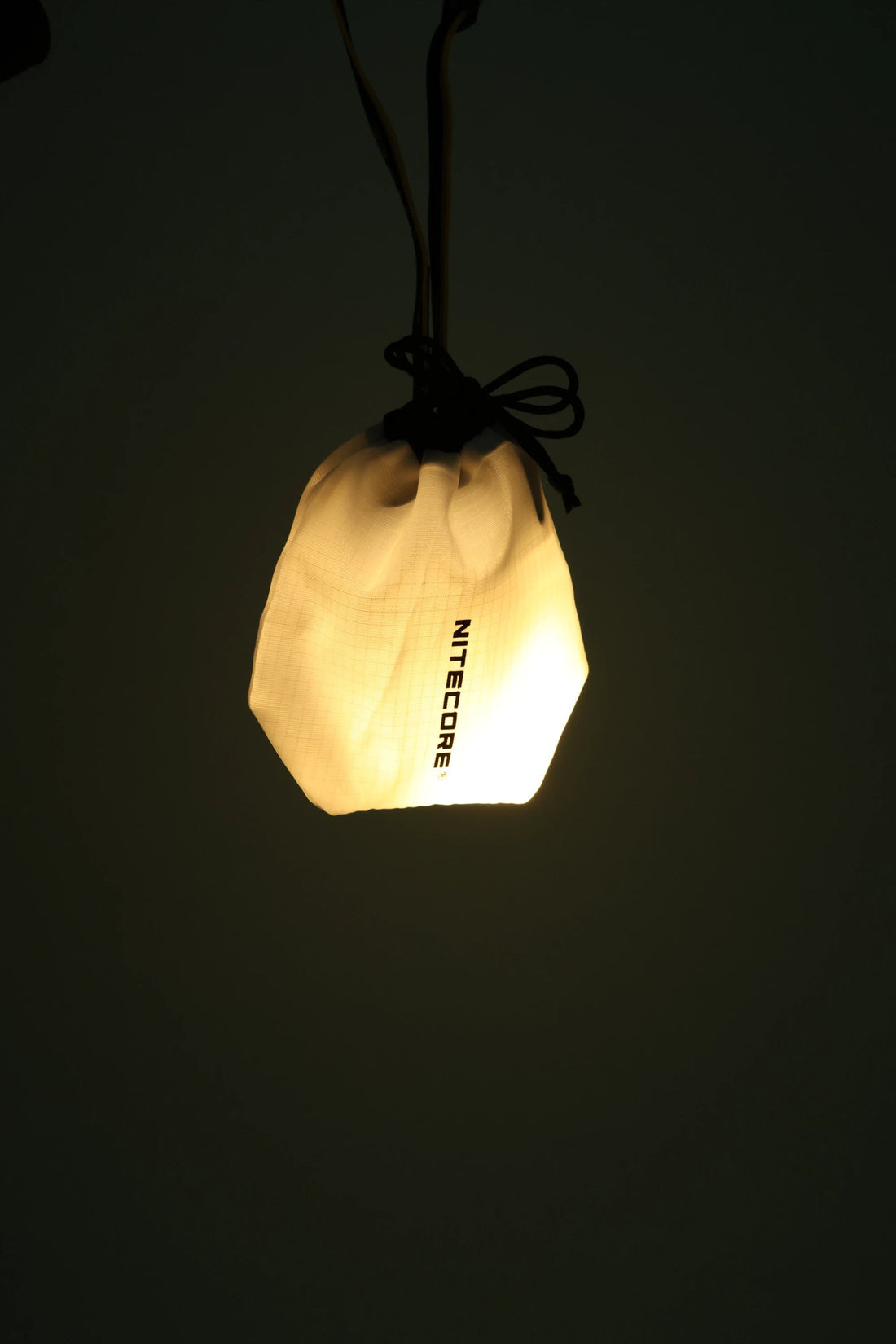 Nitecore NU25 MCT 400L - Yellow LED headlight in a drawstring bag, illuminating softly.