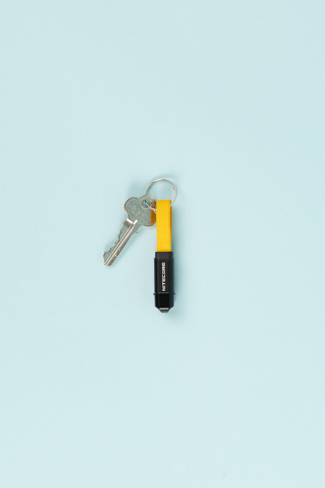 Nitecore NLink10 USB-C Fast Charging Cable attached to keyring with yellow strap and key on a light blue background.