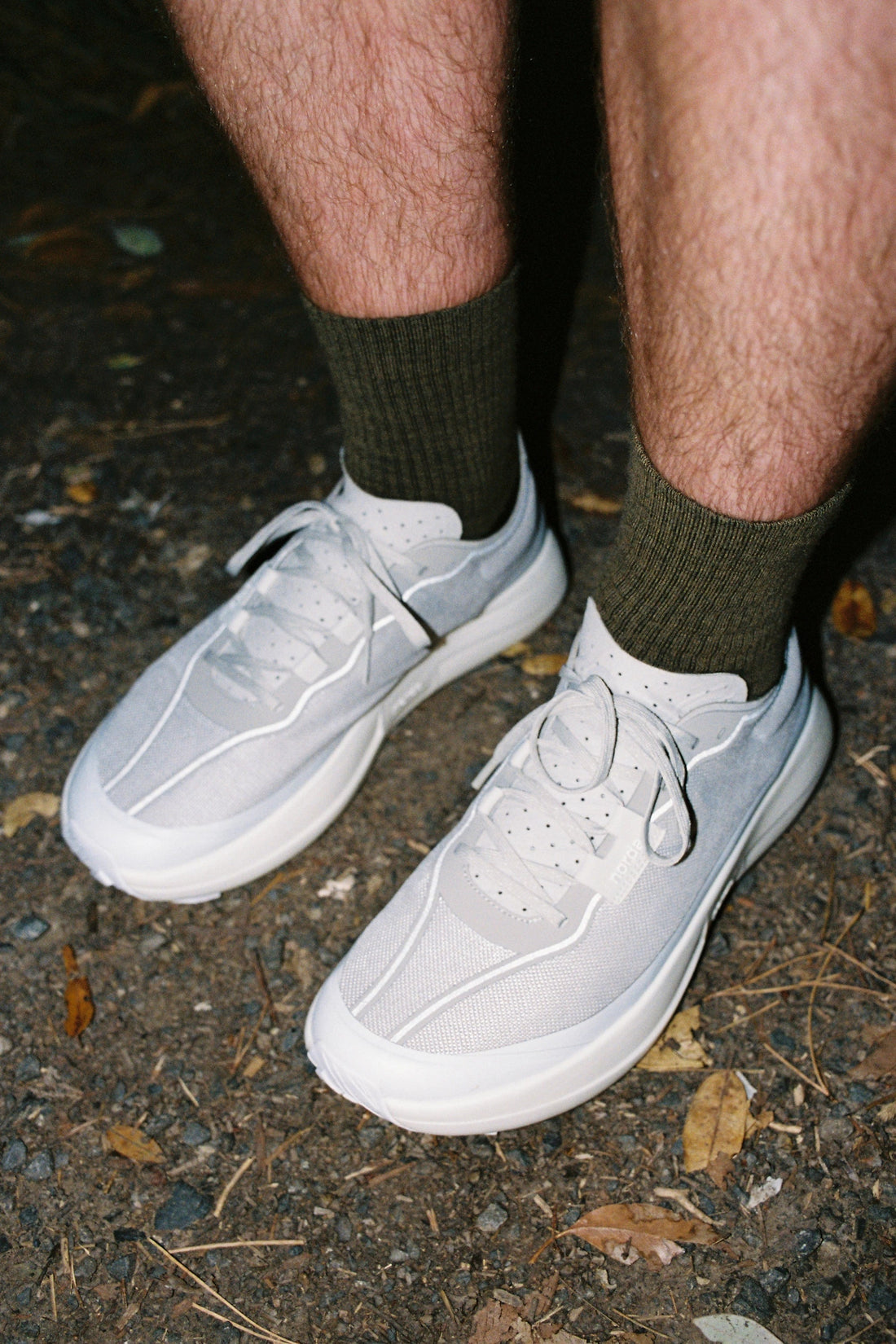 Norda 005 - Névé trail shoes worn with green socks in an outdoor setting with leaves on the ground.