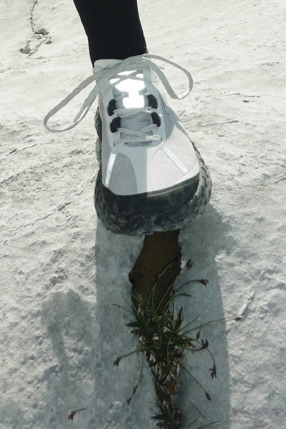 A close-up of the Norda 001A - Pewter shoe walking on rocky terrain.