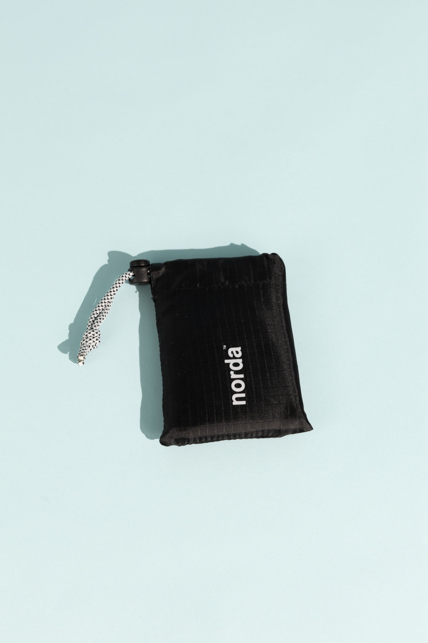 Norda 008 - Sage carrying pouch displayed on a light blue background, featuring the logo and a drawstring closure.
