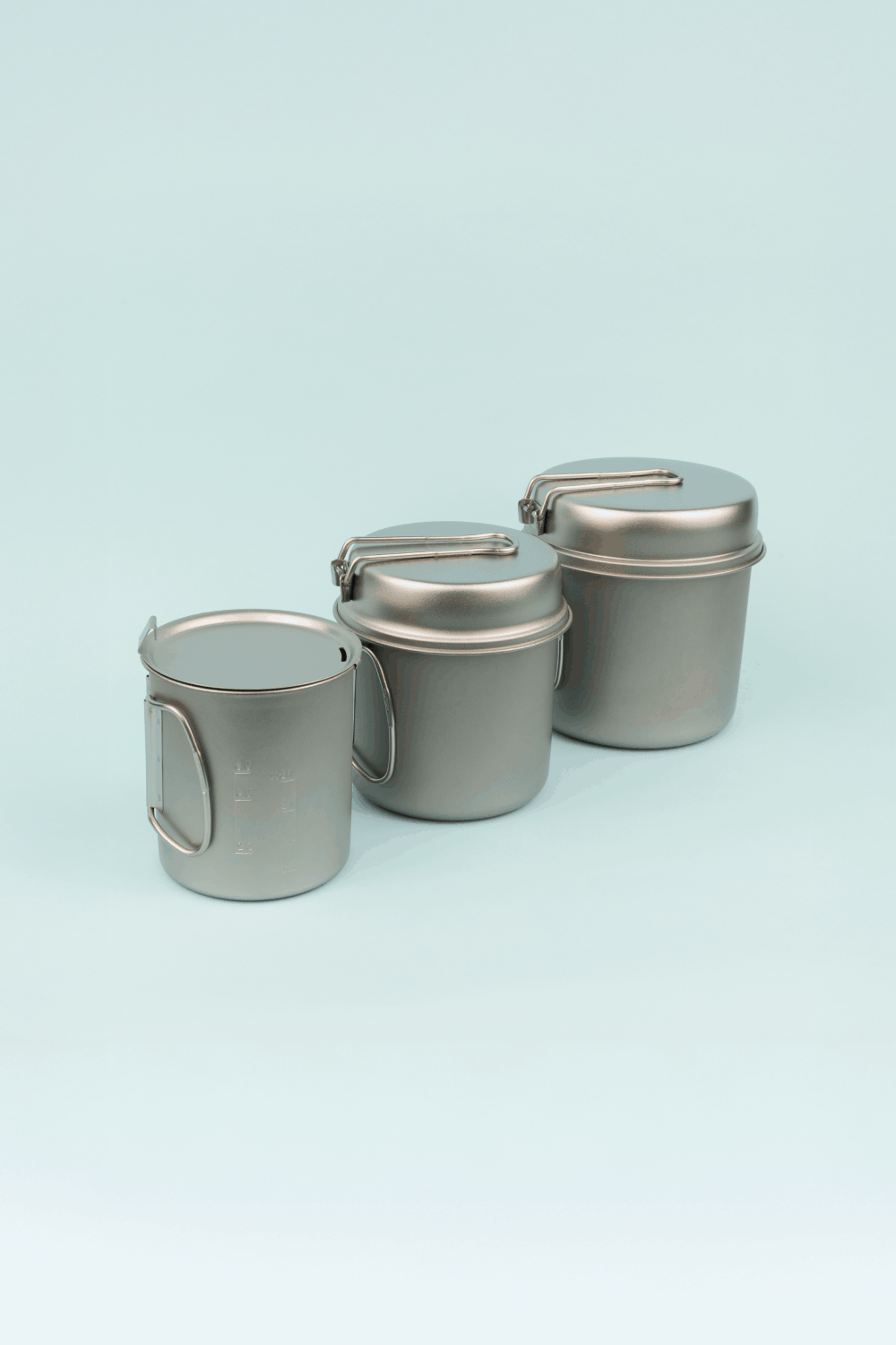 Snow Peak Nesting Pot Set featuring three ultralight titanium pots with foldable handles for outdoor cooking.