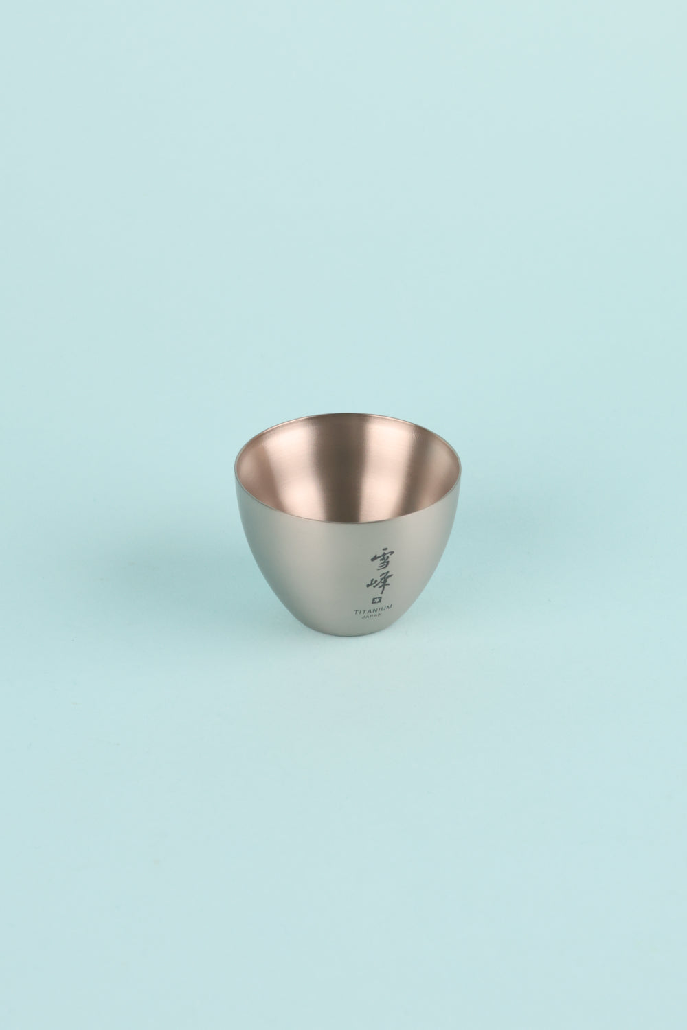 Snow Peak Titanium Sake Cup on a light blue background, featuring an elegant design for hot or cold beverages.
