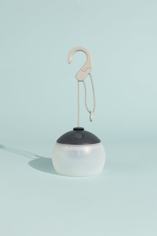 Snow Peak Rechargeable Hozuki Lantern - Night Sky hanging from a hook against a light blue background.
