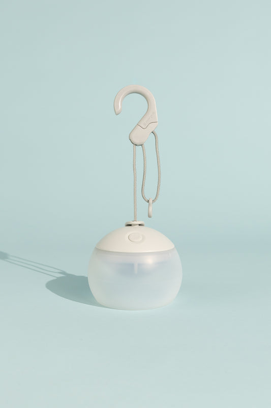 Snow Peak Rechargeable Hozuki Lantern - Morning Mist on a pastel background with a hook for hanging.