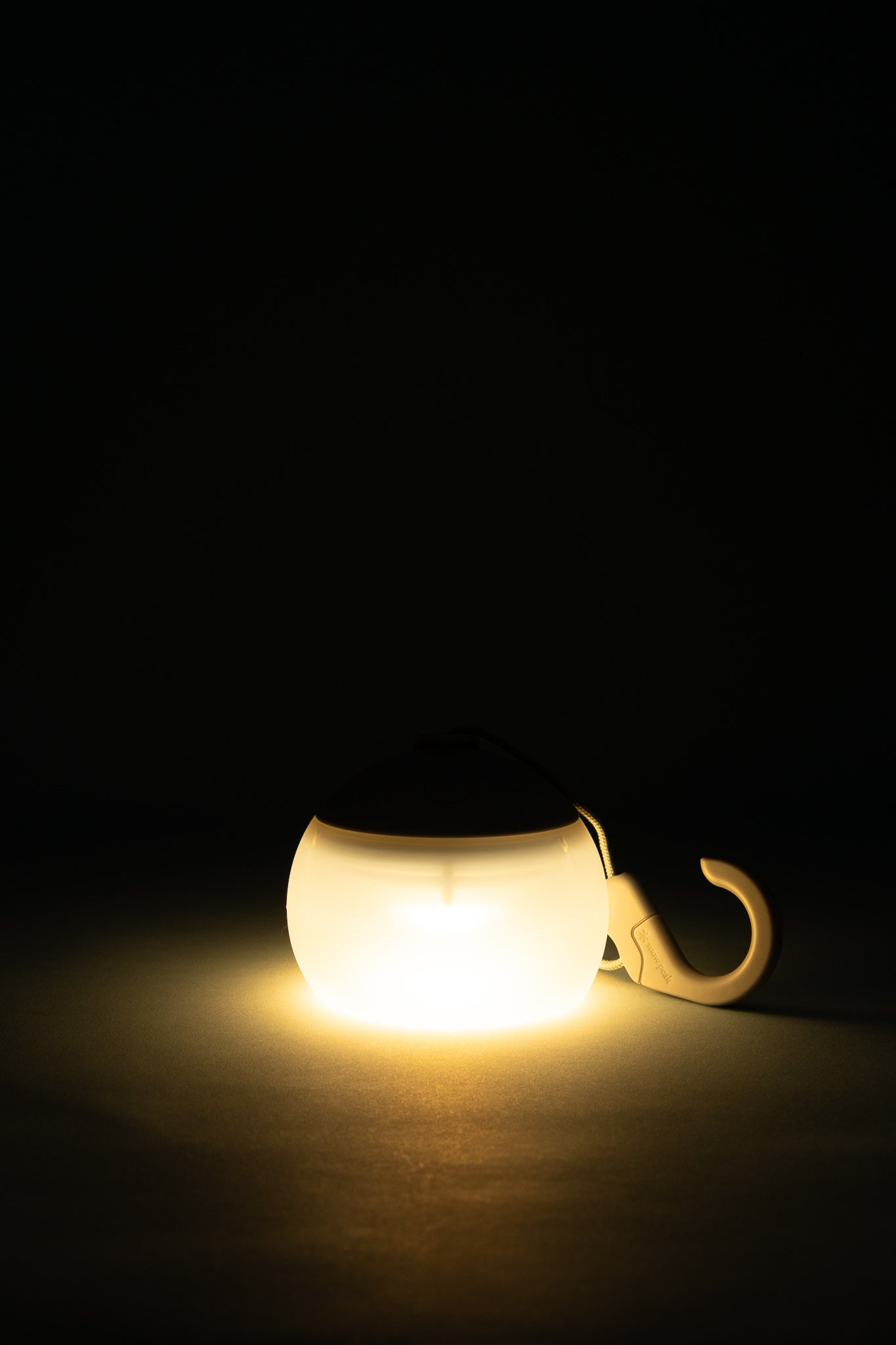 Snow Peak Rechargeable Hozuki Lantern - Morning Mist glowing softly in a dark setting.