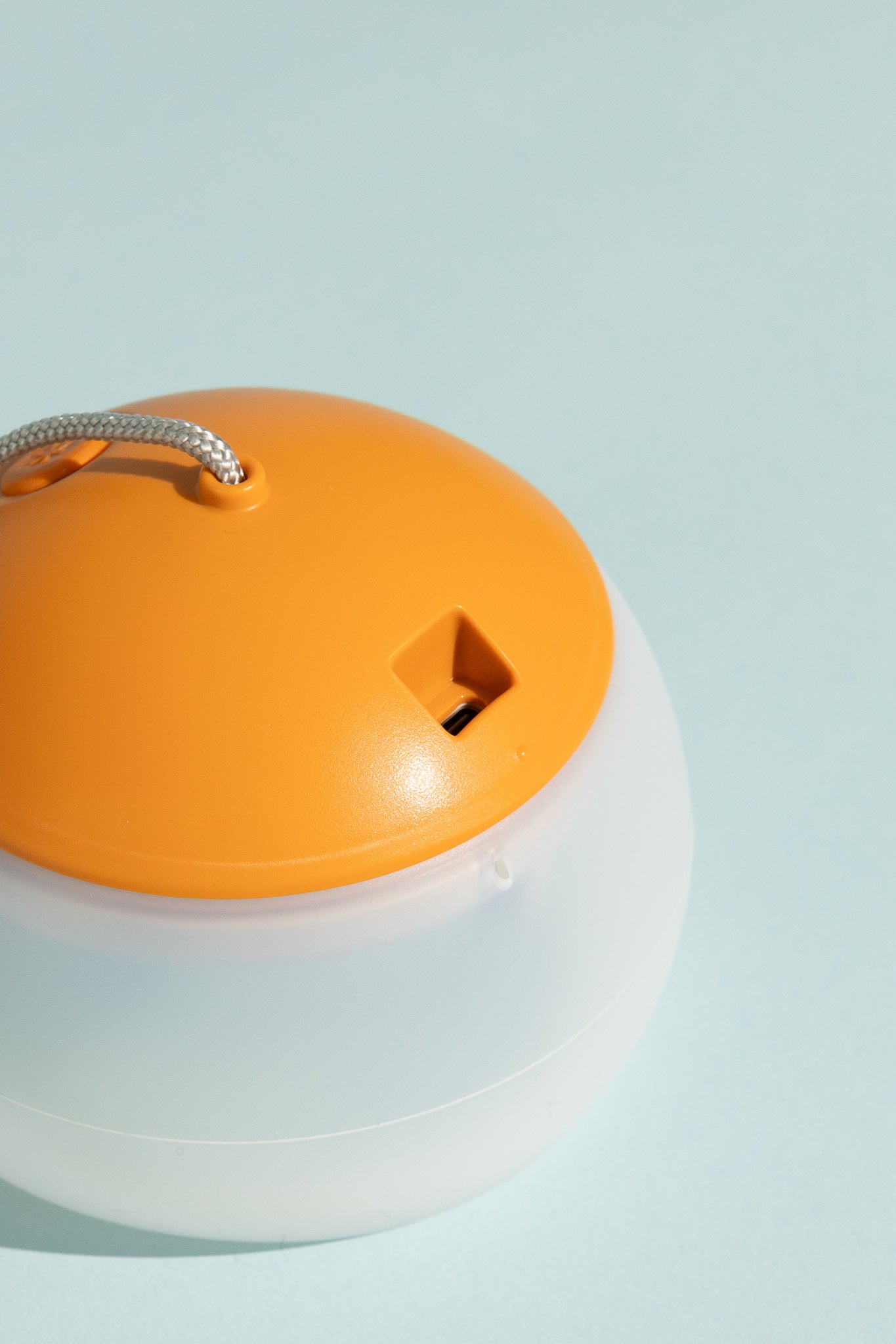 Snow Peak Rechargeable Hozuki Lantern - Twilight close-up of the orange top design against a light blue background.