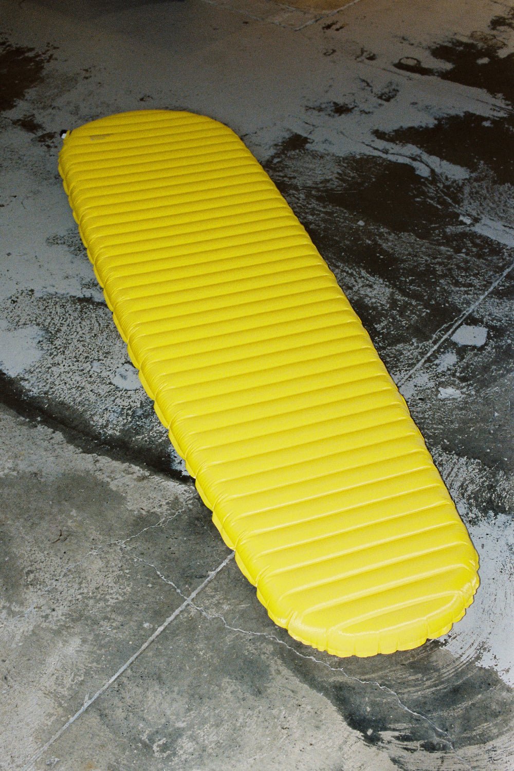 Thermarest NeoAir XLite NXT Sleeping Mat - Solar Flare, bright yellow sleeping pad on a concrete surface.