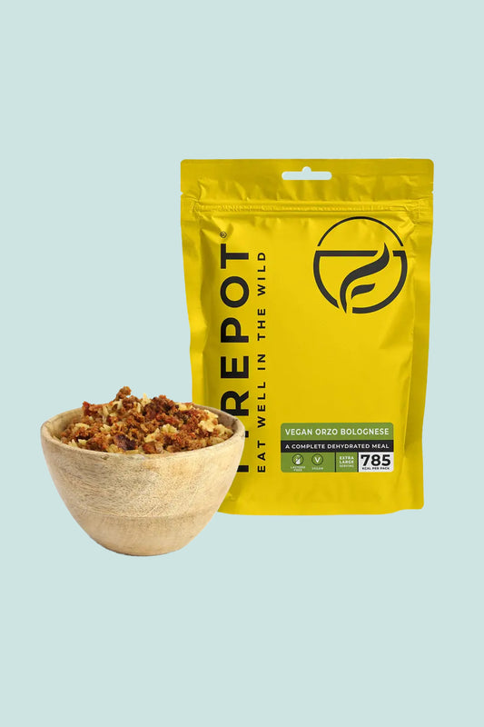 Firepot Vegan Orzo Bolognese extra large serving in a wooden bowl beside the packaging.