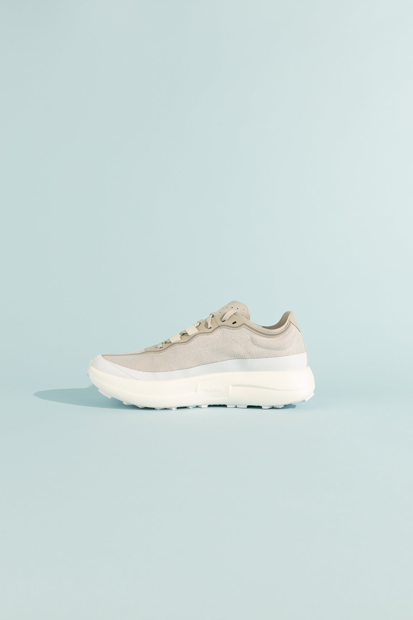 Side view of 005 - Névé trail shoe designed for stability and speed on flat terrains.