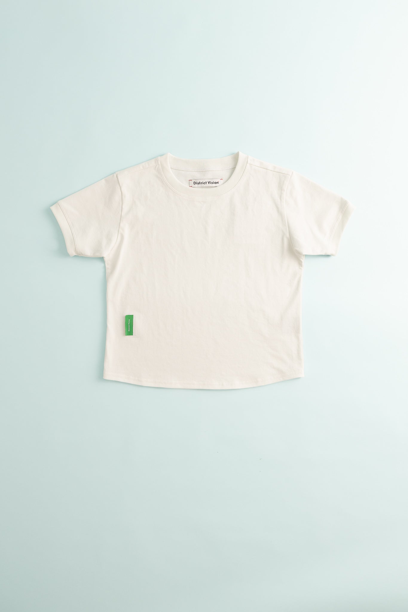 District Vision Womens Fitted Cropped T-Shirt in Off White on a light blue background.