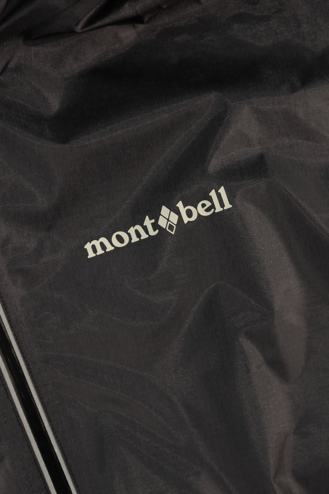 Close-up of the Montbell logo on the US Women's Versalite Jacket - Black fabric