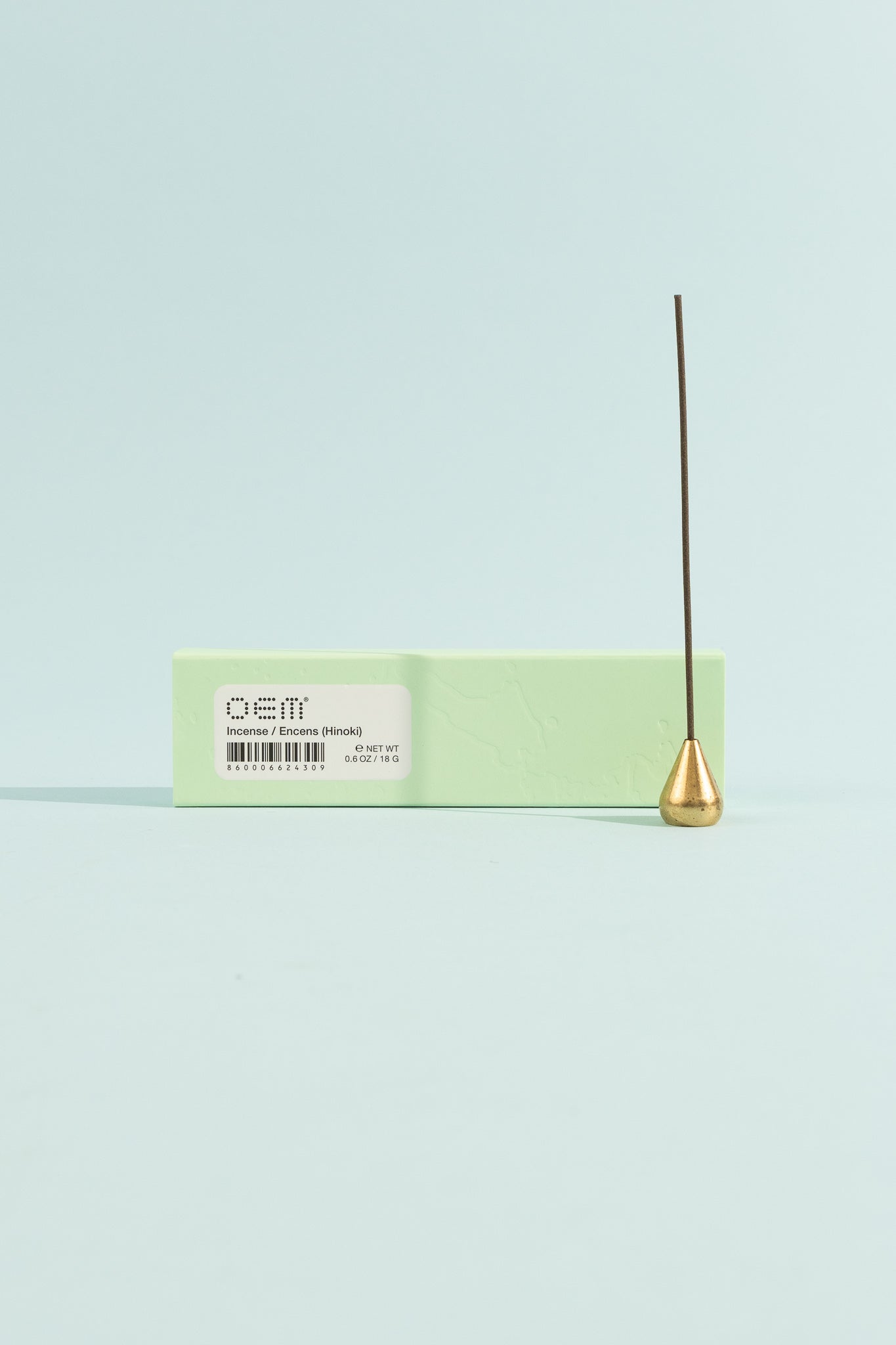OEM Incense 50 Pack - Hinoki displayed with a gold incense holder on a mint green background.