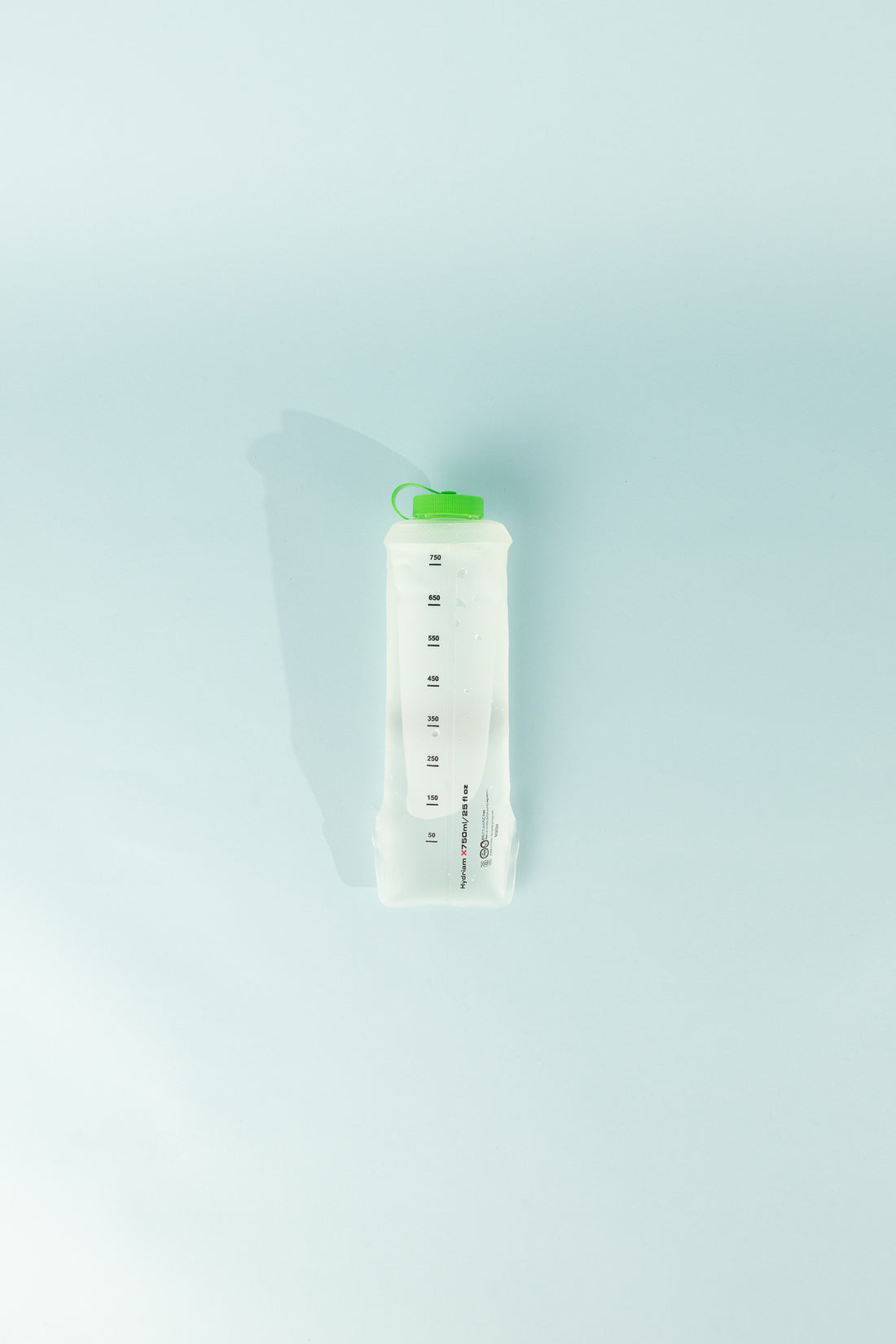 HydriamX 750ml collapsible flask with green cap and measurement markings on a light blue background.