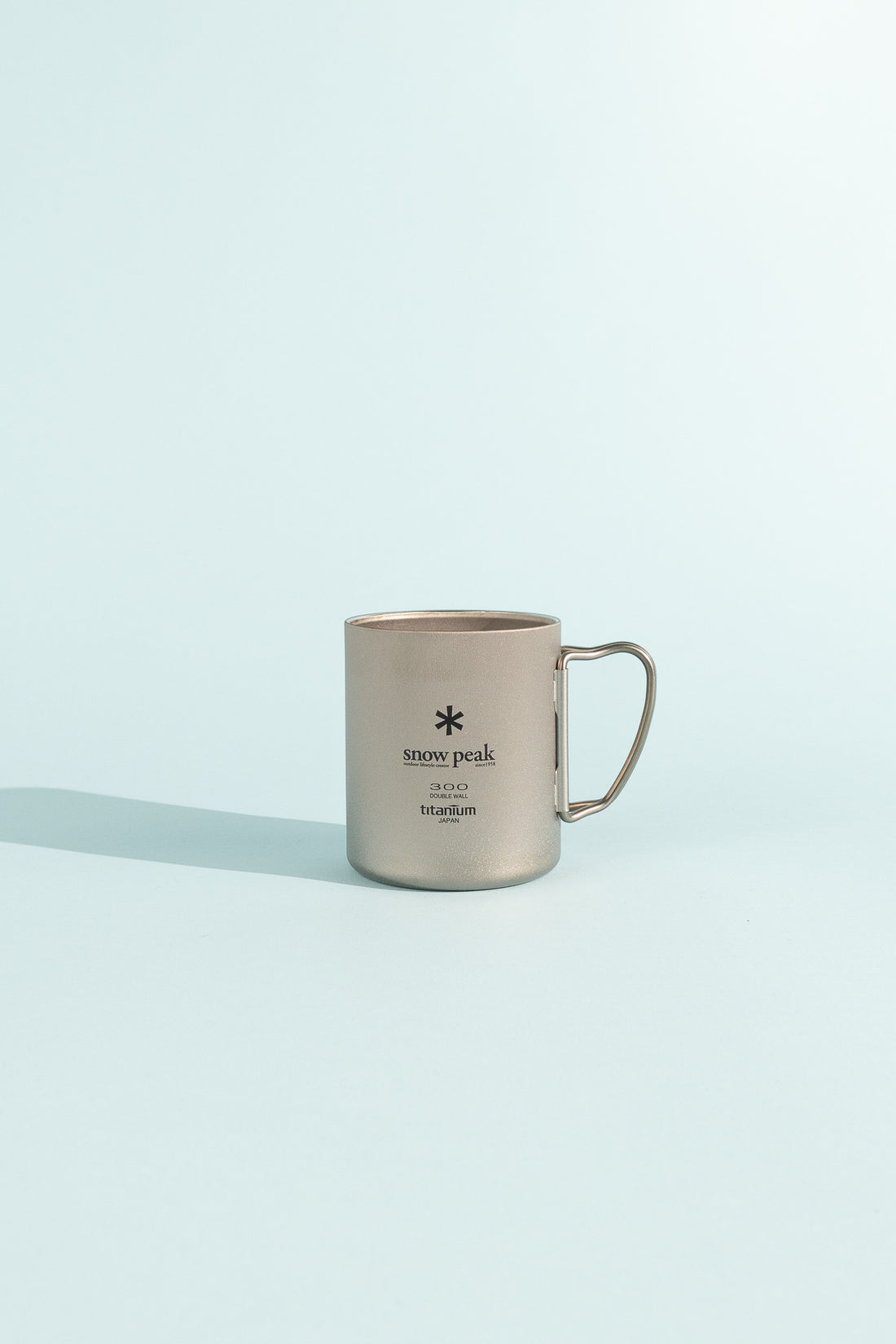 Titanium Double Wall Cup with folding handle on a light background.